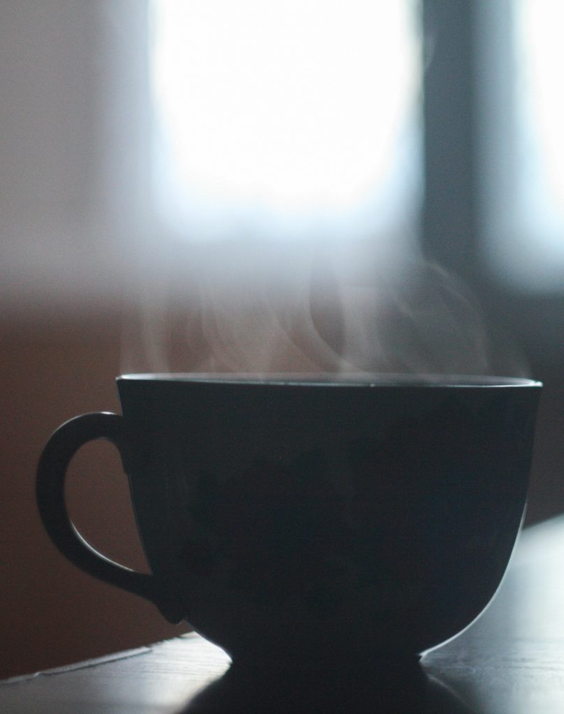 Steam rises from a dark coloured cup